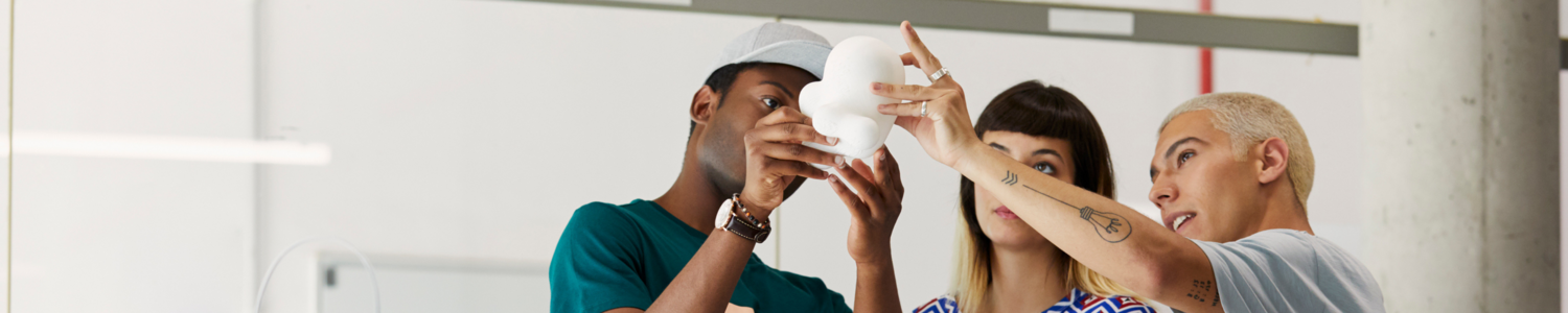 Students hold up a prototype above their heads in a studio.